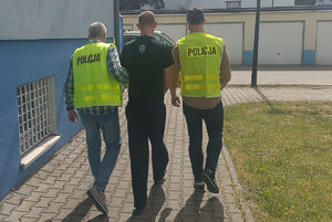 dwóch policjantów prowadzi zatrzymanego mężczyznę