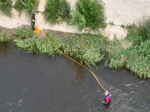 widok z góry na funkcjonariusza, który przeszukuje dno przy brzegu rzeki