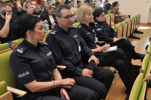 Siedzący w rzędzie krzeseł policjanci.