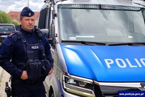 umundurowany policjant stoi przy radiowozie