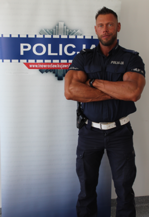 policjant w mundurze pozuje na tle ścianki