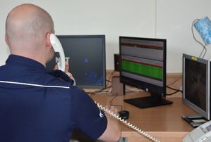 Policjant - oficer dyżurny odbiera telefon w czasie pełnienia służby - widok z tyłu