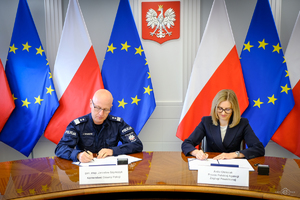 na zdjęciu gen. insp. Jarosław Szymczyk i Pani Anita Oleksiak Prezes PAŻP siedzą przy biurku i podpisują porozumienie