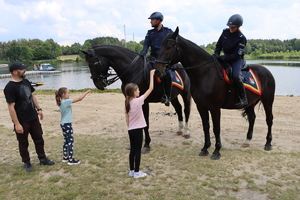 Para policjantów na koniach służbowych wraz z uczestnikami spotkania.