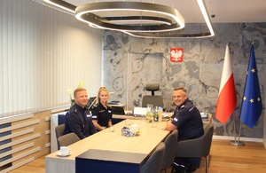 komendant wojewódzki Policji w Krakowie z policjantem i policjantką przy stole