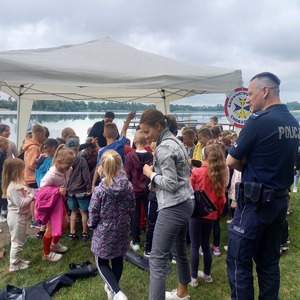 Policjant z grupą dzieci w namiocie profilaktycznym.