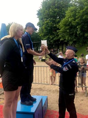 policjant wręcza puchar zawodniczce stojącej na podium