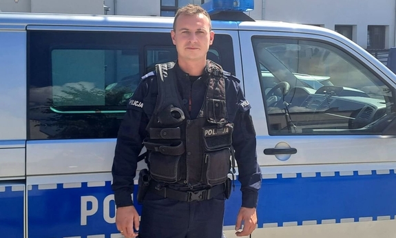 umundurowany policjant stoi na tle radiowozu