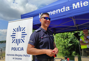 Policjant pozuje do zdjęcia w tle namiot profilaktyczny.