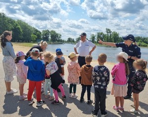 Para policjantów rozmawia z grupą dzieci i ich opiekunami.