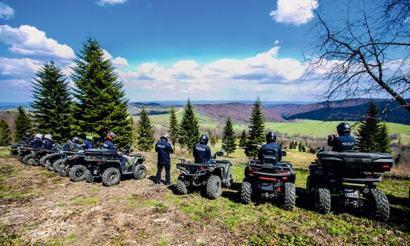 grupa umundurowanych policjantów na quadach zatrzymała się na wzgórzu