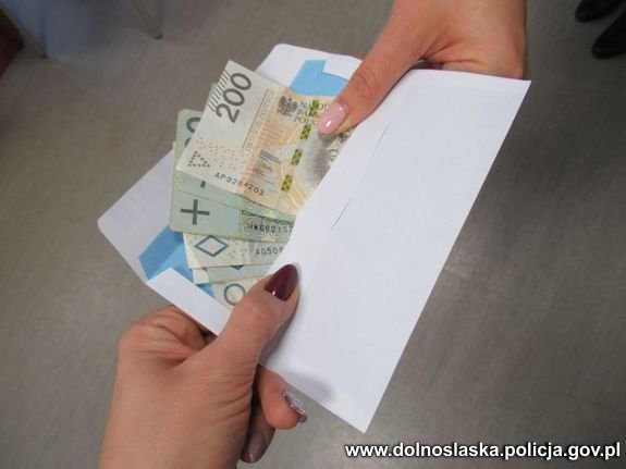 Wystające z koperty banknoty 200 i 100 złotowe przekazywane z ręki do ręki