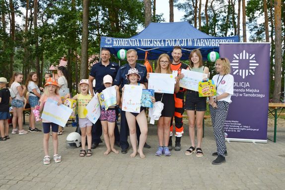 policjanci z młodzieżą pozują przy stoisku profilaktycznym Policji