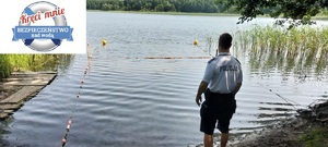 Policjant odwrócony plecami stoi na skraju akwenu wodnego.