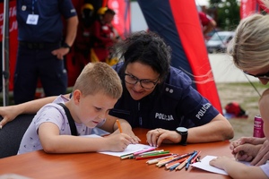 Policjantka z dzieckiem przy stoliku profilaktycznym.