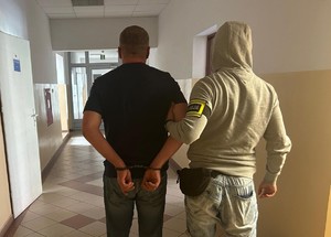 Policjant na korytarzu stoi z zatrzymanym