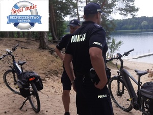 Dwóch policjantów stoi na brzegu akwenu wodnego obok nich znajdują się dwa rowery.