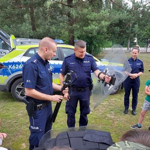 Policjanci prezentują dzieciom wyposażenie służbowe policjantów.