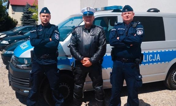 trzech umundurowanych policjantów stoi przed radiowozem