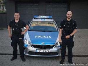 Dwaj policjanci stojący przy radiowozie