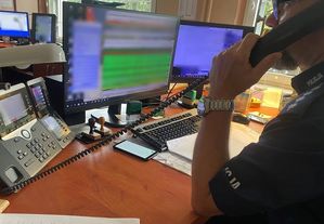 policjant siedzi przy biurku i rozmawia przez służbowy telefon