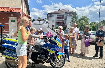 Dzieci oglądają policyjny motocykl na którym siedzi chłopiec