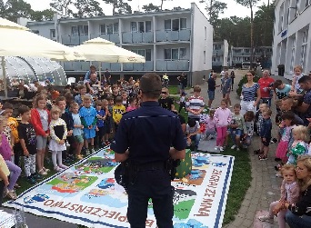 Policjant stojąc w otoczeniu dzieci