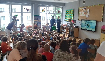 Policjanci stojący pośród gromady dzieci siedzących w klasie