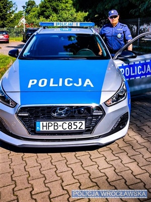 umundurowany policjant stoi przy radiowozie