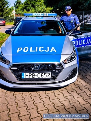 umundurowany policjant stoi przy radiowozie