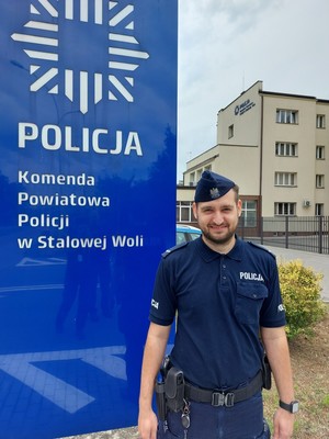 umundurowany policjant stoi przed budynkiem komendy powiatowej Policji