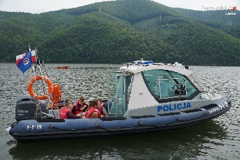 Grupka dzieci ubranych w kapoki siedzące w policyjnej motorówce.