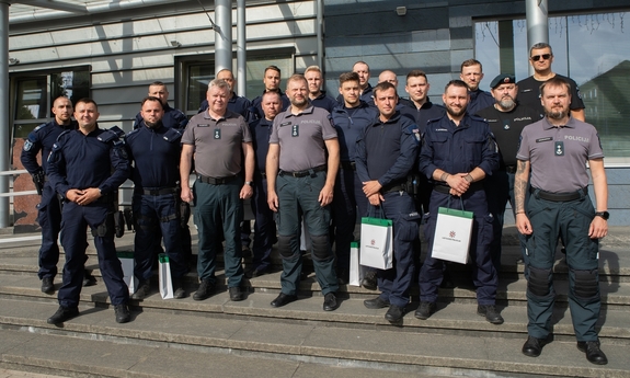 Grupa polskich i litewskich policjantów pozuje do zdjęcia stojąc na schodach wejściowych do budynku.