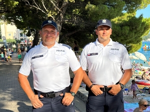 dwaj polscy policjanci w Chorwacji, w tle widoczna promenada nadmorska, drzewa i plaża