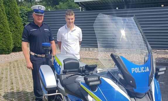 uczeń klasy mundurowej stoi z policjantem przy motocyklu policyjnym