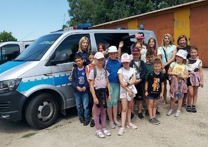 Policjantka pozuje do zdjęcia z grupą dzieci i ich opiekunami.