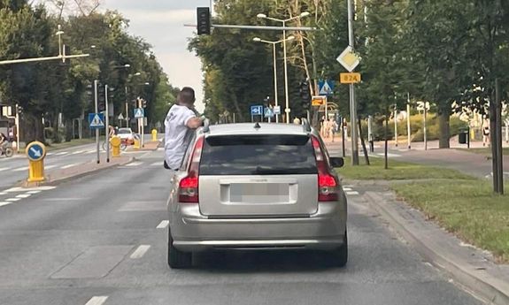 Na zdjęciu widzimy mężczyznę, który w czasie jazdy wysiadł zza kierownicy auta na zewnątrz pojazdu