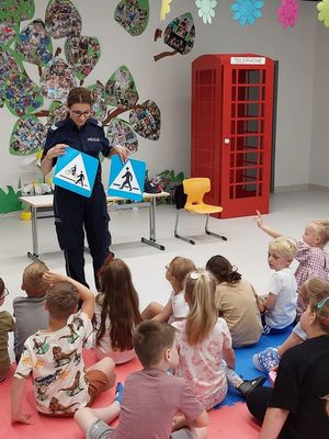 Policjantka zapoznaje grupę dzieci ze znakami drogowymi.