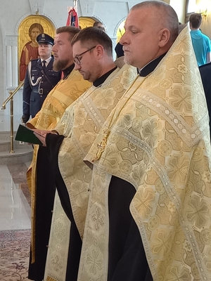 trzej duchowni podczas nabożeństwa, w tle policjant