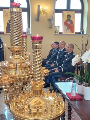 na pierwszym planie złote świeczniki, w tle policjanci siedzący w ławkach podczas nabożeństwa