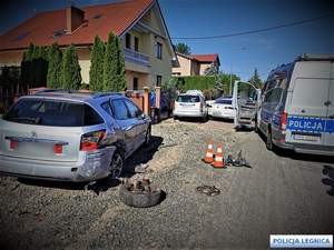 Radiowóz stojący koło samochodu osobowego z zerwanym tylnym kołem