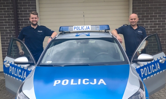 dwaj policjanci stoją przy radiowozie policyjnym