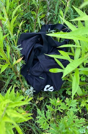 leżąca w zaroślach czarna torba sportowa