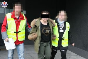 policjanci prowadzą zatrzymaną kobietę