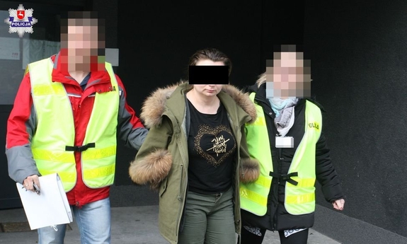 policjanci prowadzą zatrzymaną kobietę