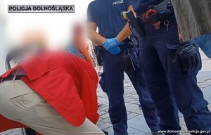 zatrzymany mężczyzna w czerwonej marynarce z policjantami