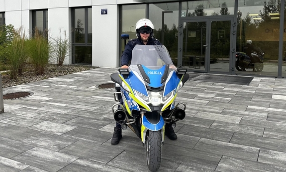 policjant na motocyklu przed budynkiem komendy policji