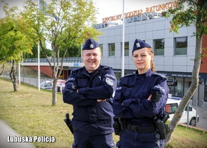 umundurowany policjant i policjantka pozują do zdjęcia przed szpitalnym oddziałem ratunkowym