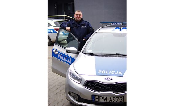 policjant przy radiowozie w tle budynek komendy