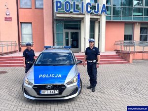 Dwoje policjantów stoi przy radiowozie